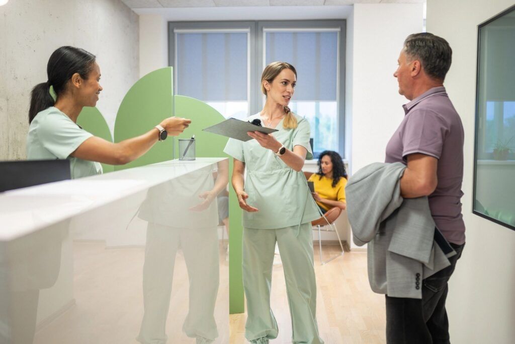 Front desk team greeting a patient as he arrives at a bright healthcare reception