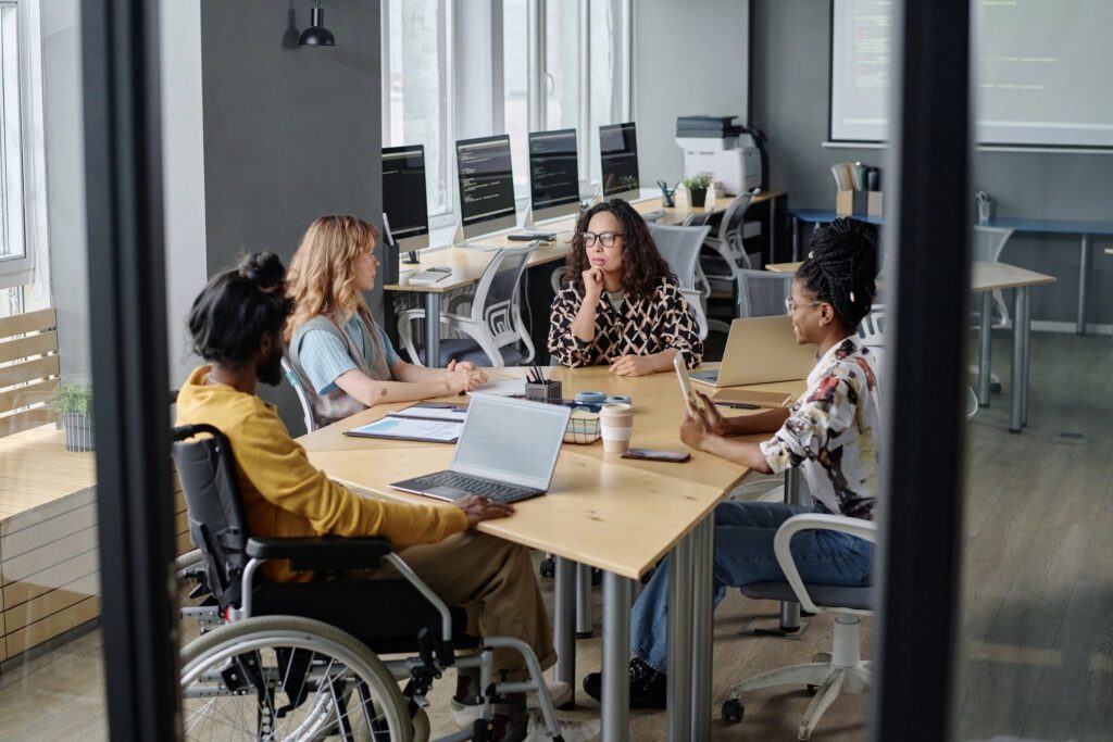 Diverse Programmers Discussing Business Affairs at Desk in Modern Urban Office